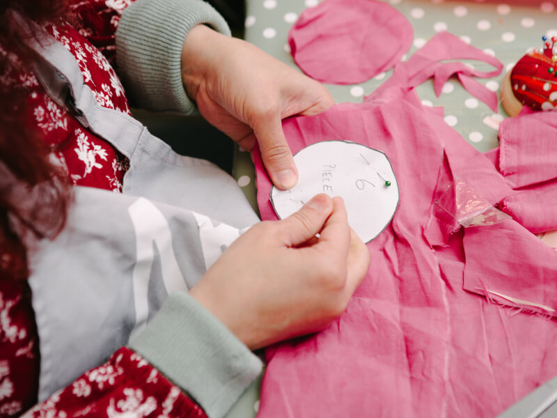 Woman pinning paper label to a piece of pink fabric
